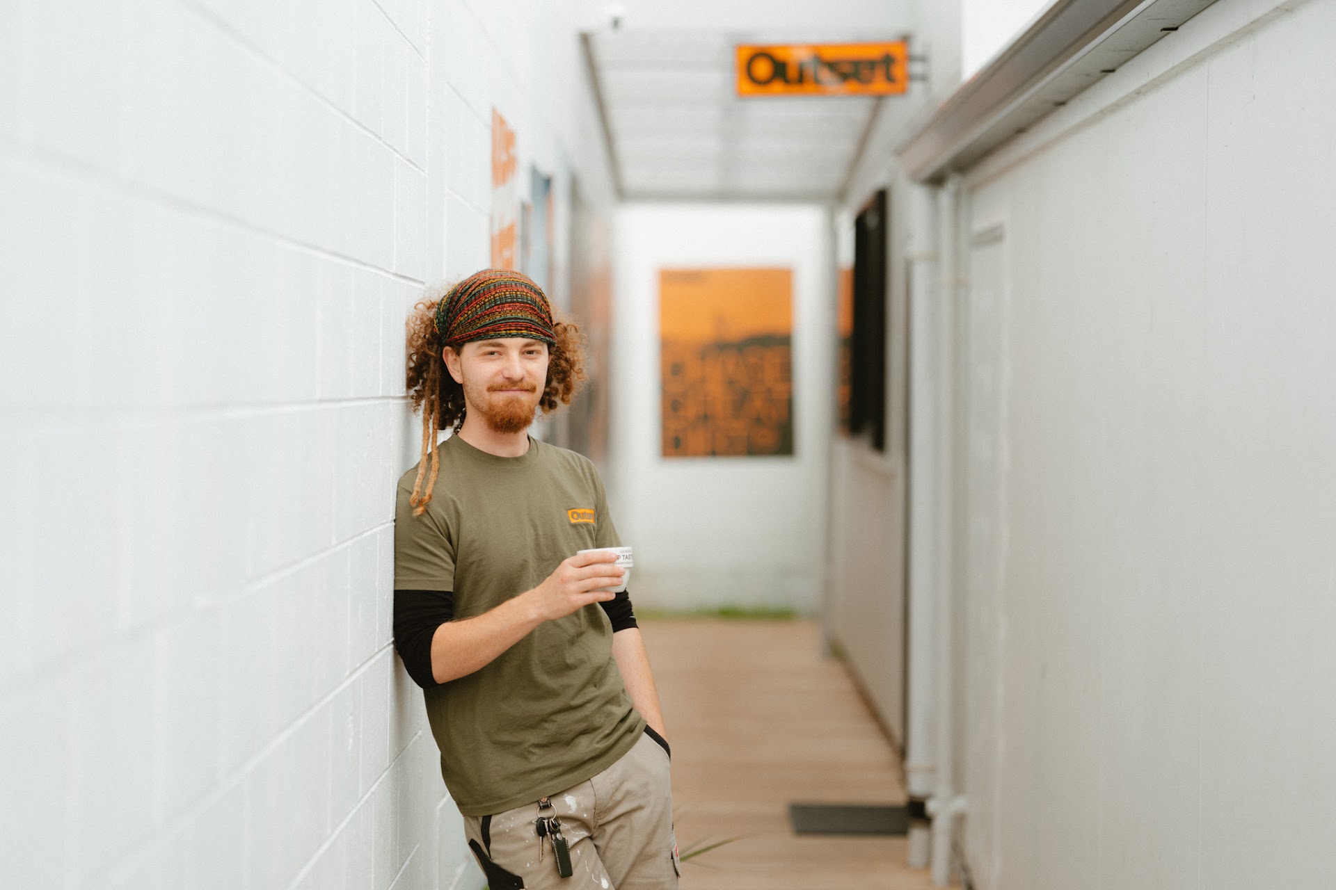 Outset staff member with a fresh coffee in the shop hallway