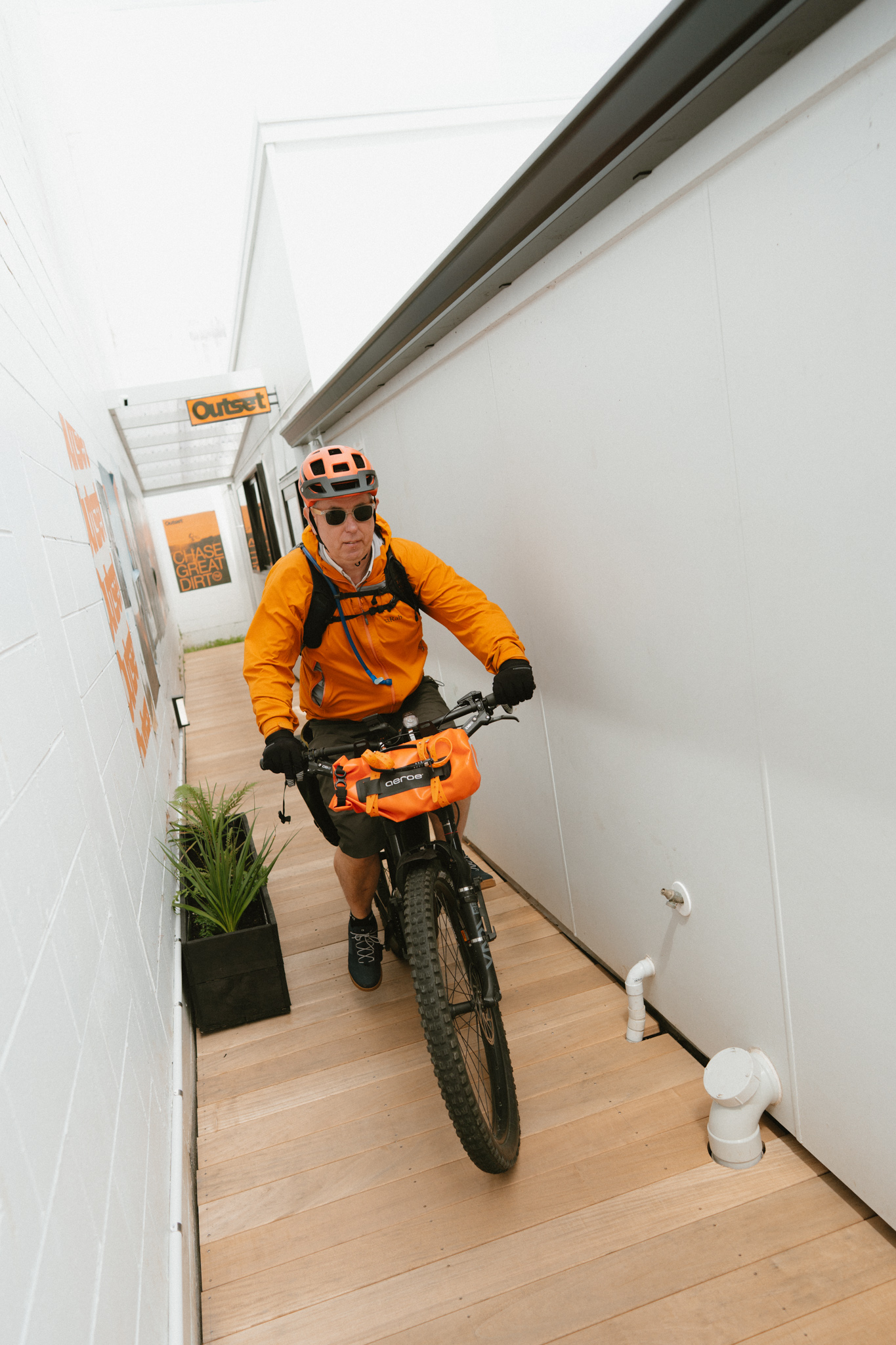 Rider wheeling a mountain bike through the gallery hallway at Outset