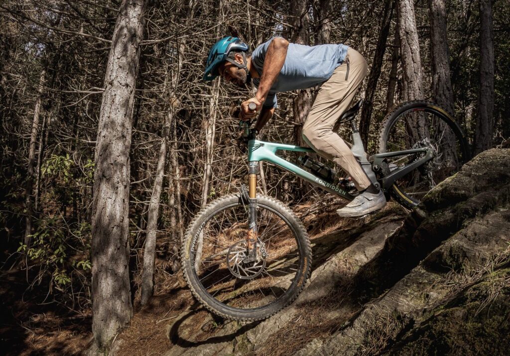 Mountain biker cornering hard on a wooded trail