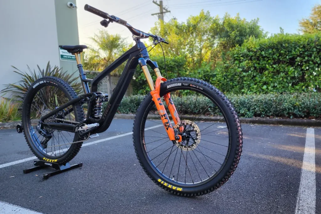 Black full-suspension mountain bike with an orange fork, built by Outset