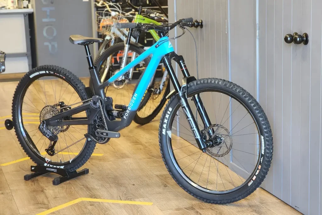 Cyan and black full-suspension mountain bike on display in the Outset store