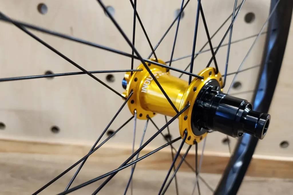 Close-up of a gold rear hub laced to a black rim on a custom-built wheel